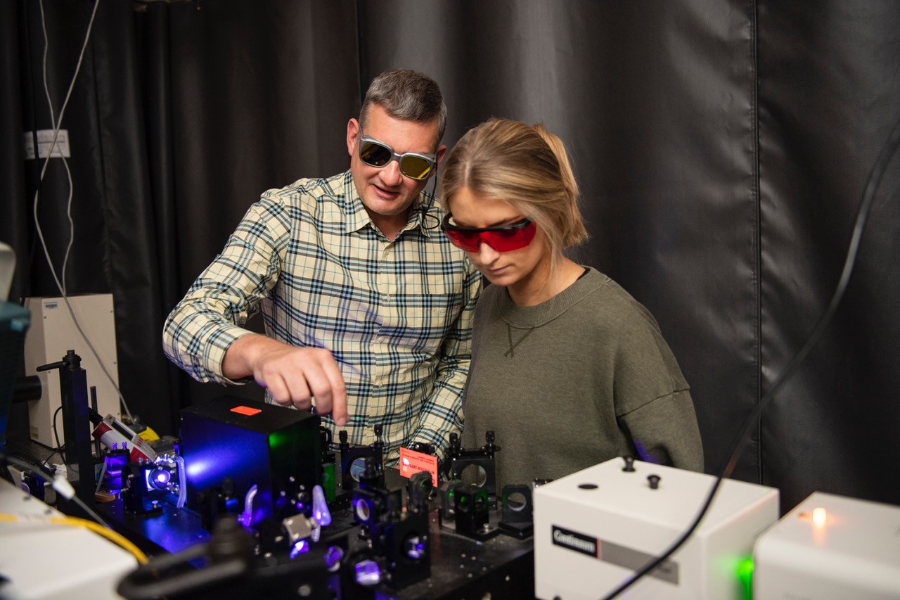 Professor and student wearing protective glasses using lasers in a lab