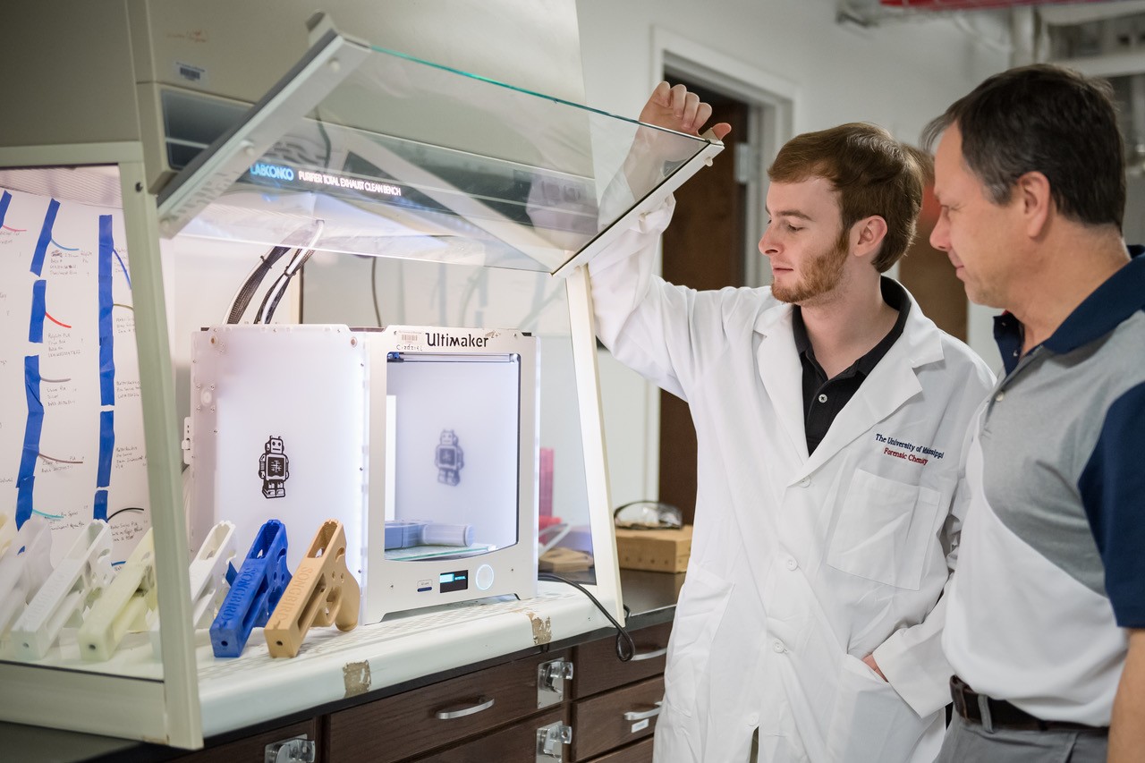 Two scientists looking at a instrument in a laboratory hood